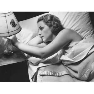  Young Woman Lying on Bed, Turning Off Lamp on Night Table 