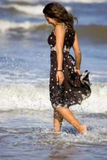 Woman walking in the waves on a beach in a clearance dress