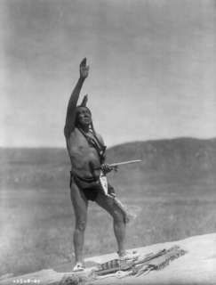 : Dakota man, wearing breechcloth, holding pipe, with right 